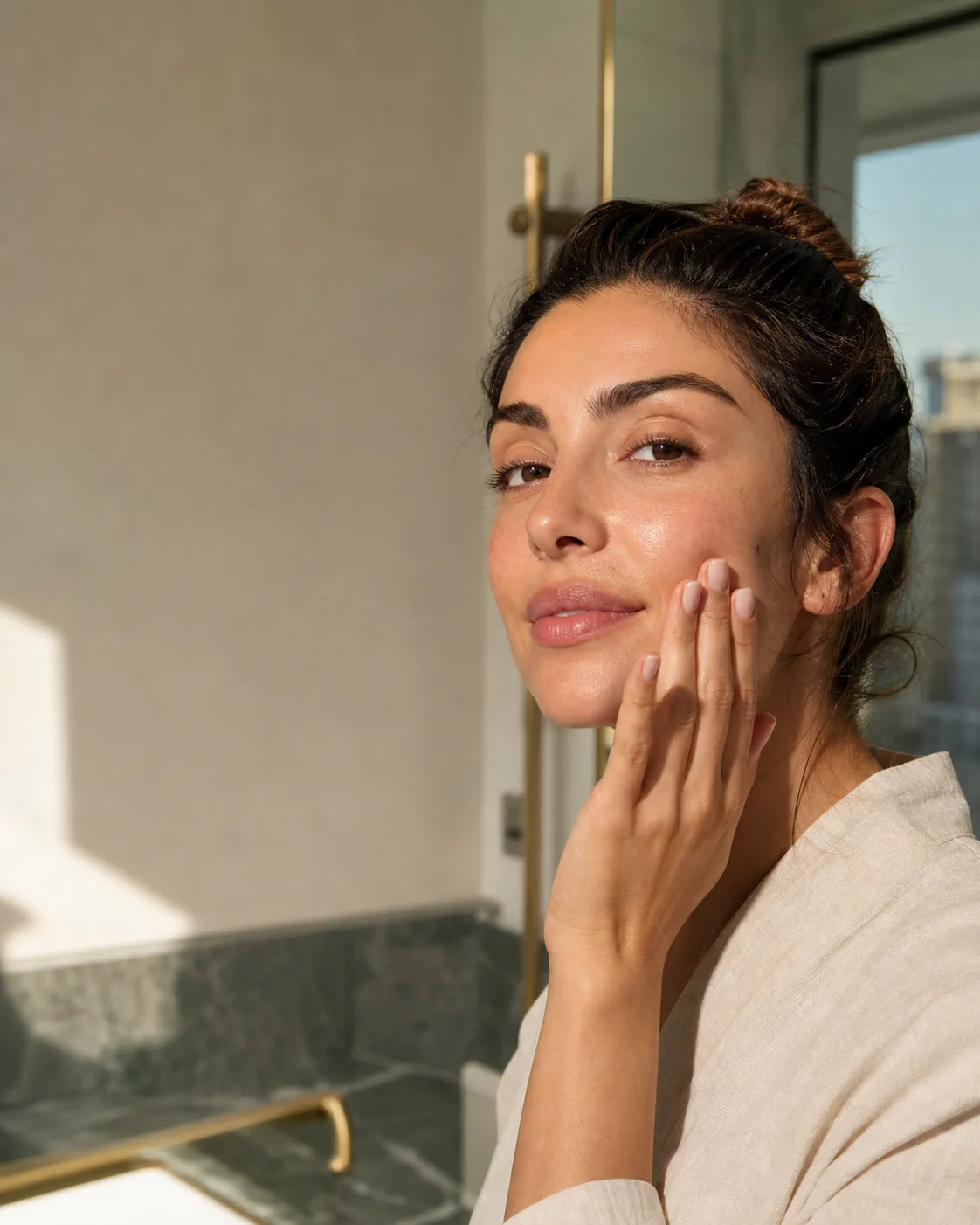 Woman applying cream during a sunlit morning skincare routine
